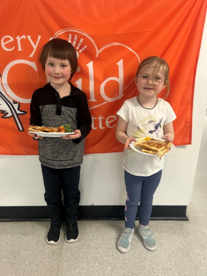 Two children holding plates of food
Description automatically generated