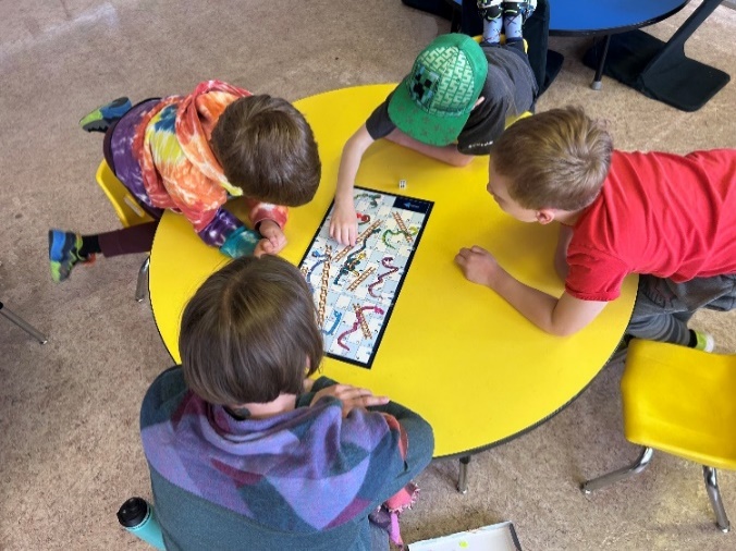 A group of kids playing a game on a yellow table
Description automatically generated
