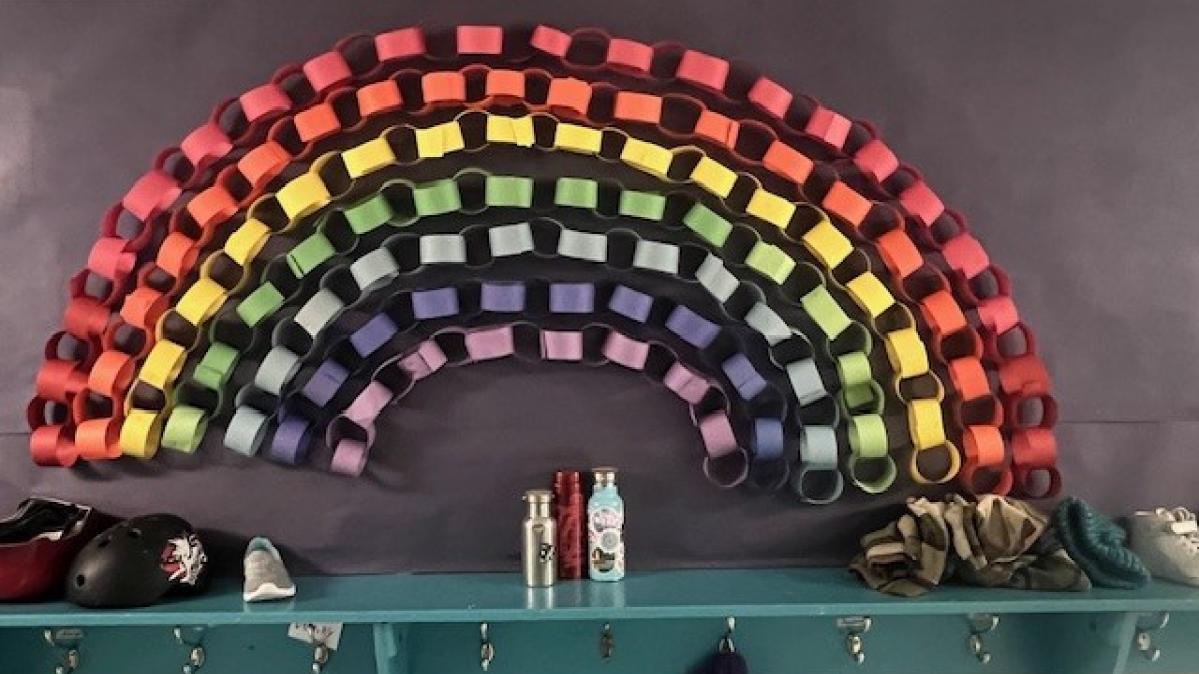 A rainbow made of coloured paper attached to an elementary school wall.