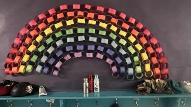 A rainbow made of coloured paper attached to an elementary school wall.
