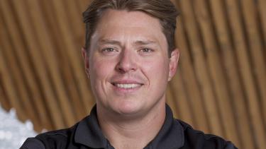 A man with short brown hair in a black shirt