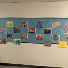Abstract artwork on a blue background in an elementary school hallway.