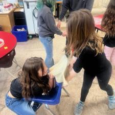 Young students stretching a hide for a drum