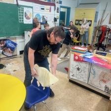 A man stretches a hide over the back of a chair 