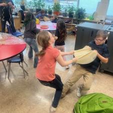 Two young students stretch a hide together