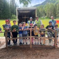 Elementary school students stand on a wooden bridge in a school yard