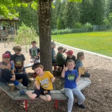 Elementary students sit on a bench built around a tree